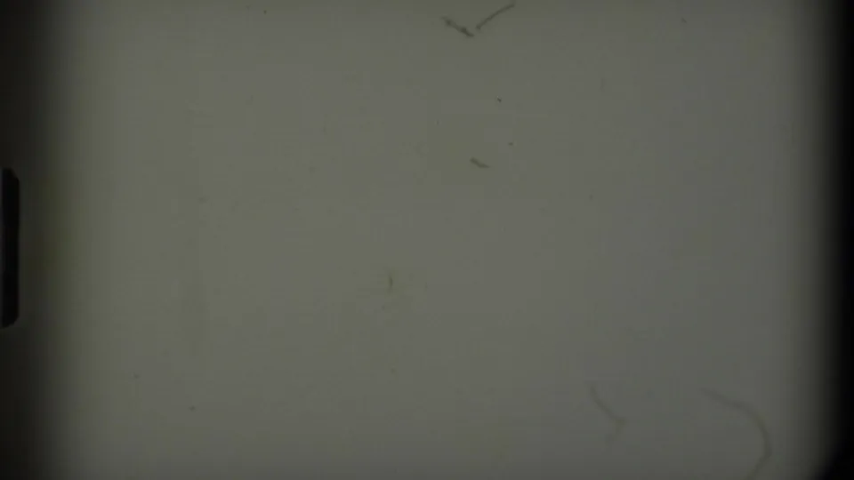 A transitional 8mm frame shows pale exposed film with dust marks and a dark rounded film edge.