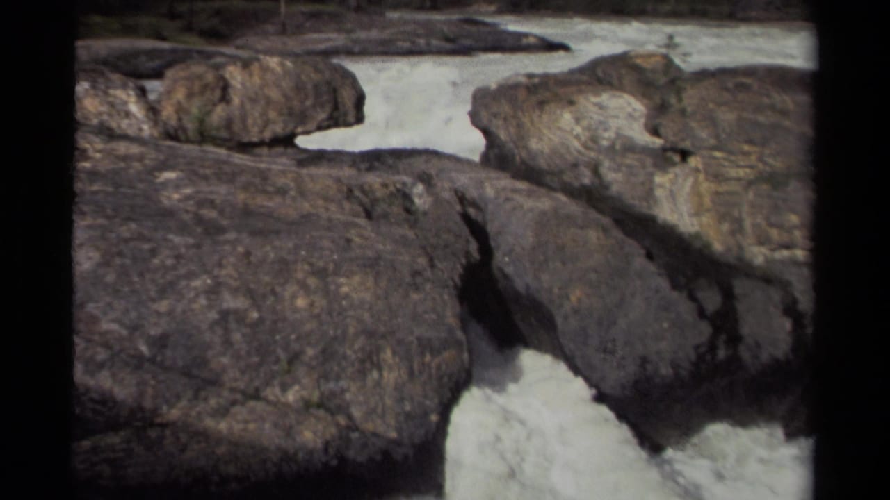1979 Canada 8mm frame showing white water moving through massive dark rocks in a rugged outdoor setting.