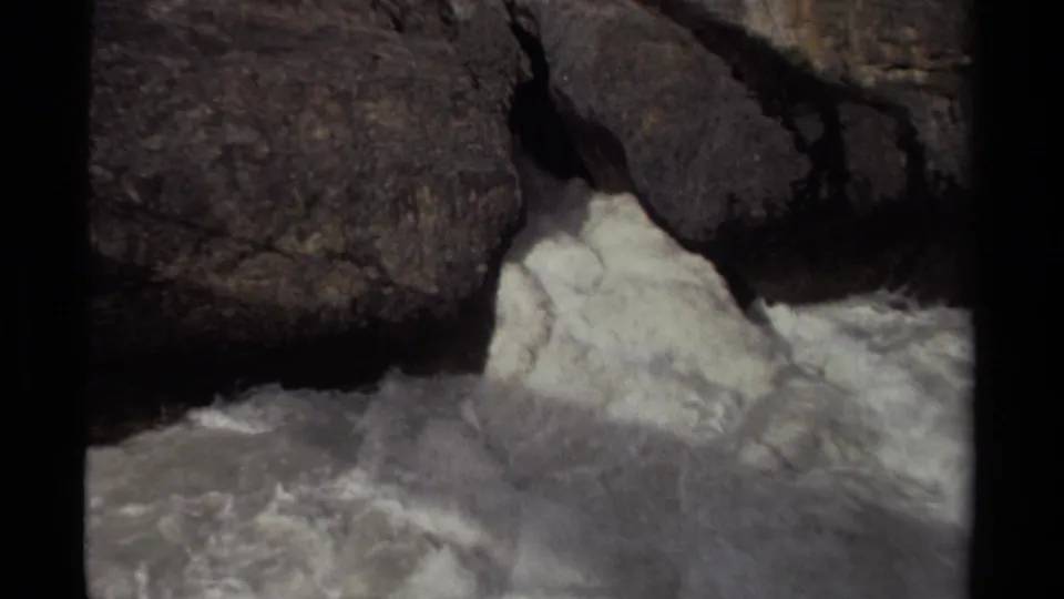 1979 Canadian home-movie frame with frothy water churning below large dark boulders.