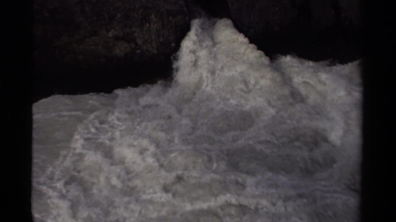 Foamy rapids churn beneath dark rock formations in this 1979 Canada home-movie frame.