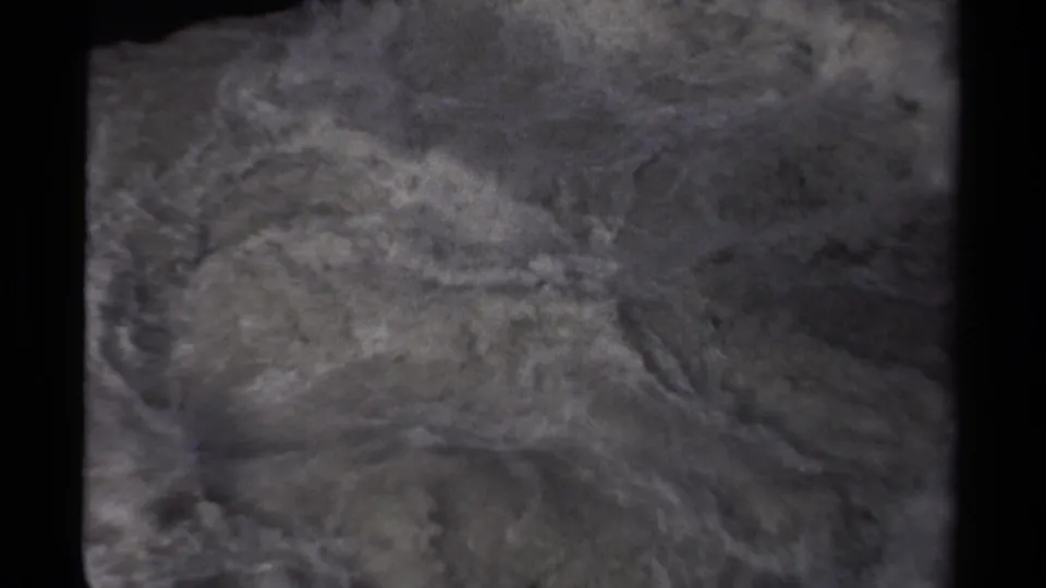 Close 8mm view of turbulent gray-white water moving below dark rocks in Canada, 1979.