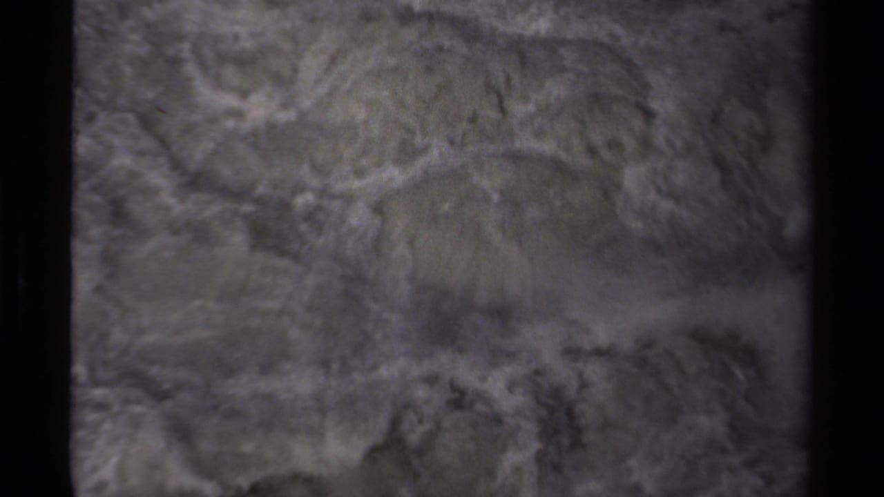 Soft 8mm view of churning Canadian river water, with pale foam patterns and dark bank edges.