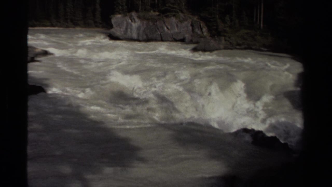 Foamy river water rushing over rocks between dark canyon edges.