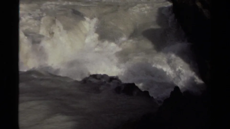 1979 Canadian 8mm frame with a close, shadowed view of churning river foam around rugged rocks.