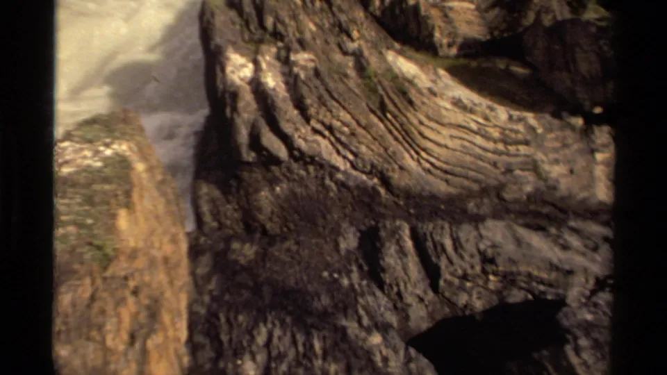 1979 Canada 8mm frame showing a close rocky surface with visible layers, mossy patches, and nearby waterfall mist.