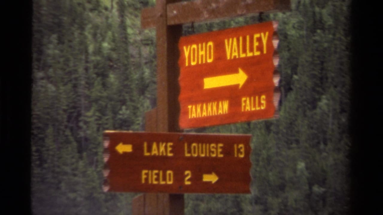 1979 Canada 8mm frame showing wooden park-style signs for Yoho Valley, Takakkaw Falls, Lake Louise, and Field against forest.