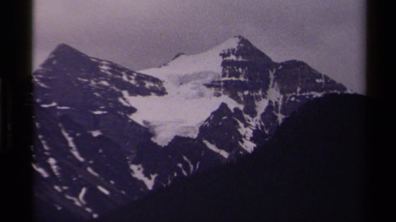 Close view of snow-covered mountain peaks with dark slopes below and film borders at the sides.