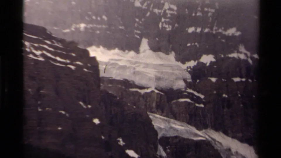 1979 Canadian 8mm frame showing a glacier and snowfields beneath a steep, shadowed mountain face.