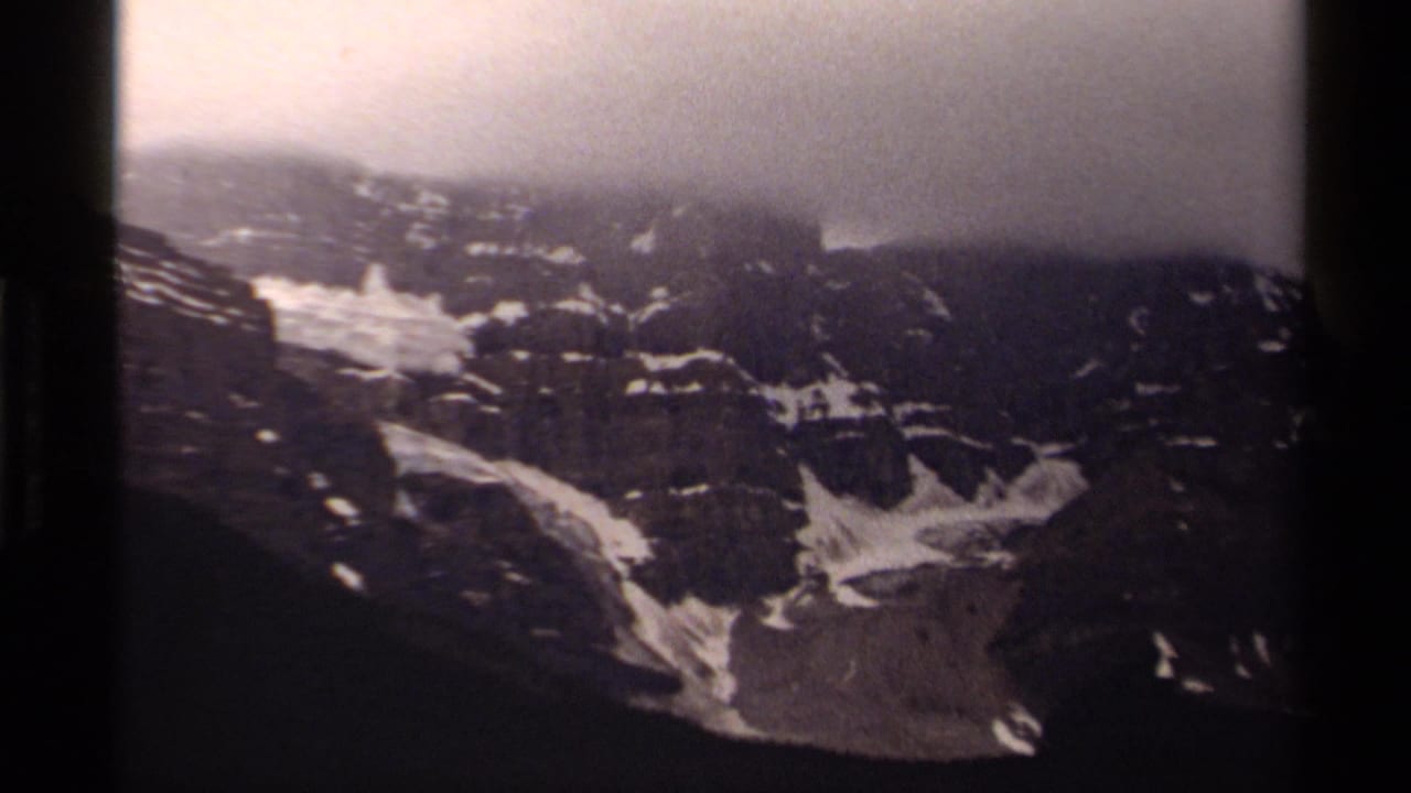 Dark mountain ridge with snow patches beneath a low overcast sky.