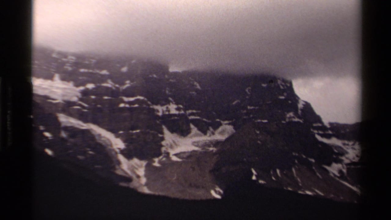 1979 Canadian 8mm view of jagged rock faces, lingering snow, and dense cloud over the mountain top.