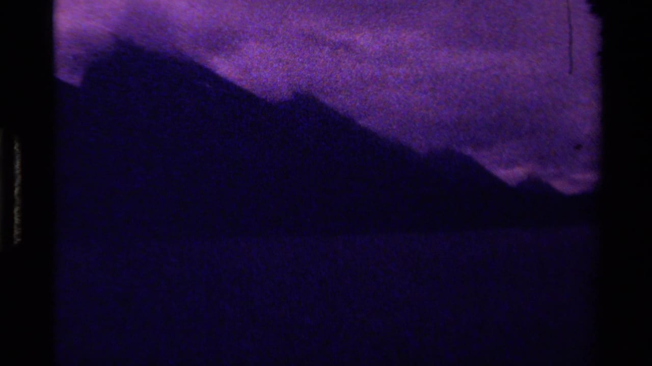 1979 Canadian 8mm frame showing purple sky above silhouetted mountains and a dark lake or water surface.