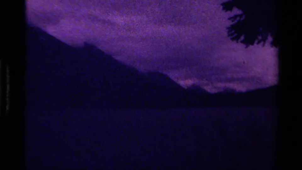 1979 Canadian 8mm landscape frame showing purple clouds, a dark mountain slope, water below, and a tree silhouette.