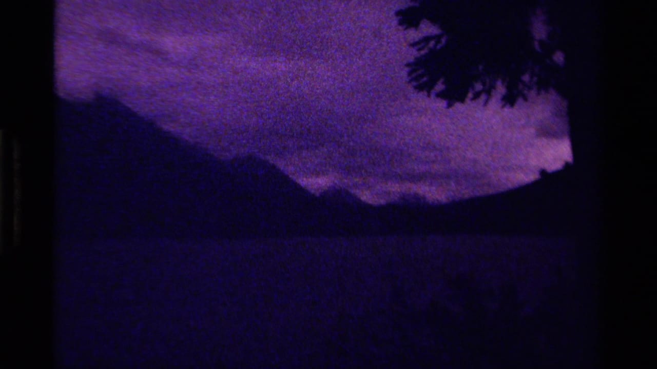 Canadian 8mm home-movie frame from 1979 showing distant mountains in low light, heavy grain, and a purple-blue cloudy sky.