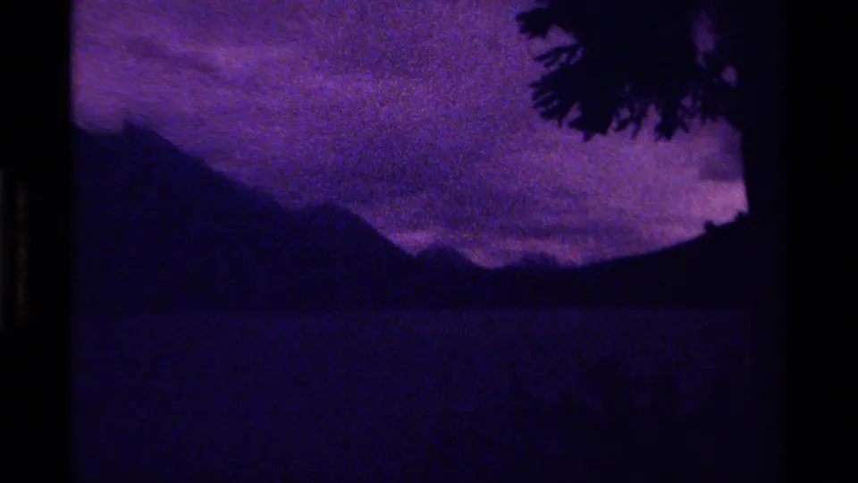 Canadian 8mm home-movie frame from 1979 showing distant mountains in low light, heavy grain, and a purple-blue cloudy sky.