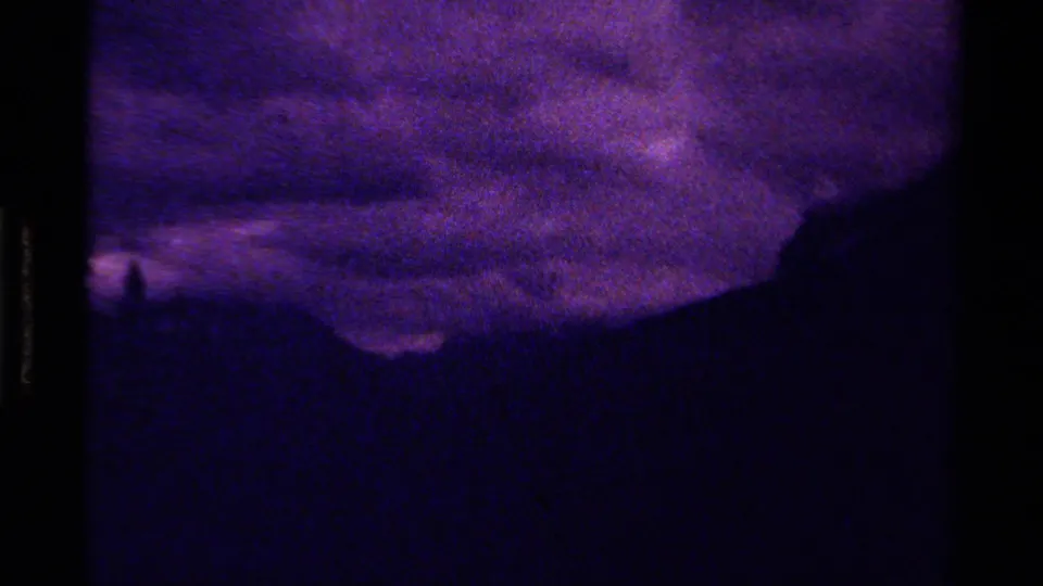 Vintage 8mm frame from Canada, 1979, showing purple cloud bands over a dark mountain silhouette and heavily shadowed foreground.
