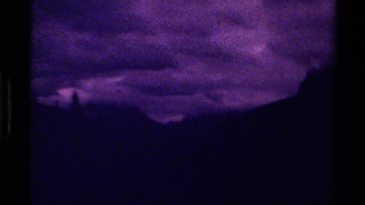 1979 Canadian 8mm frame showing a dark mountain silhouette under heavy purple clouds.