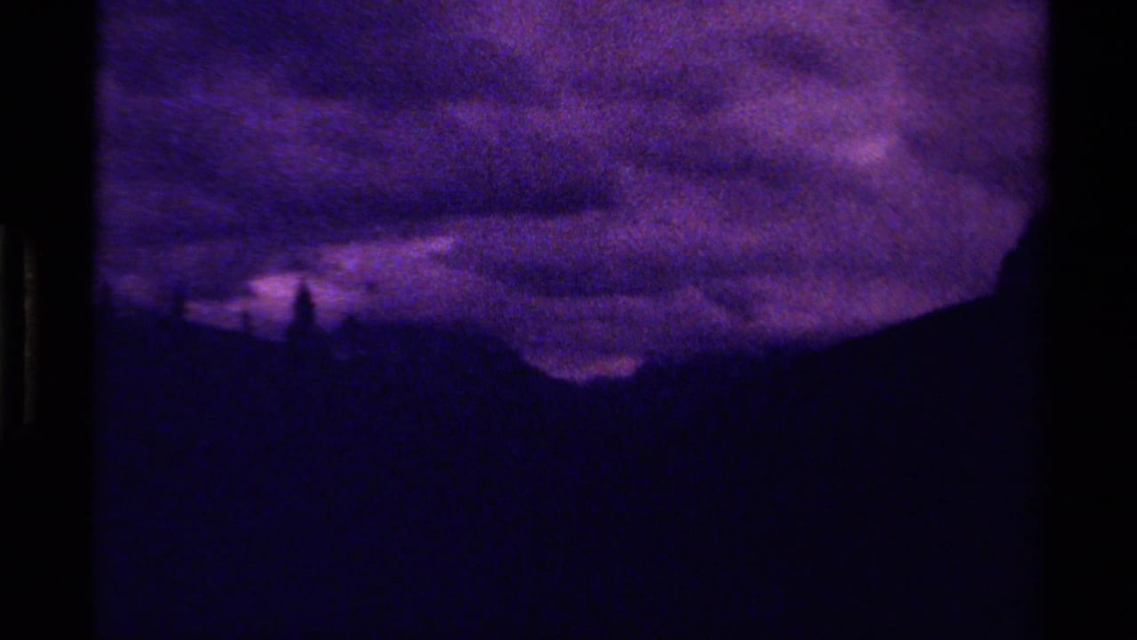 1979 Canadian 8mm frame with a shadowed mountain slope and a purple, cloud-heavy sky.