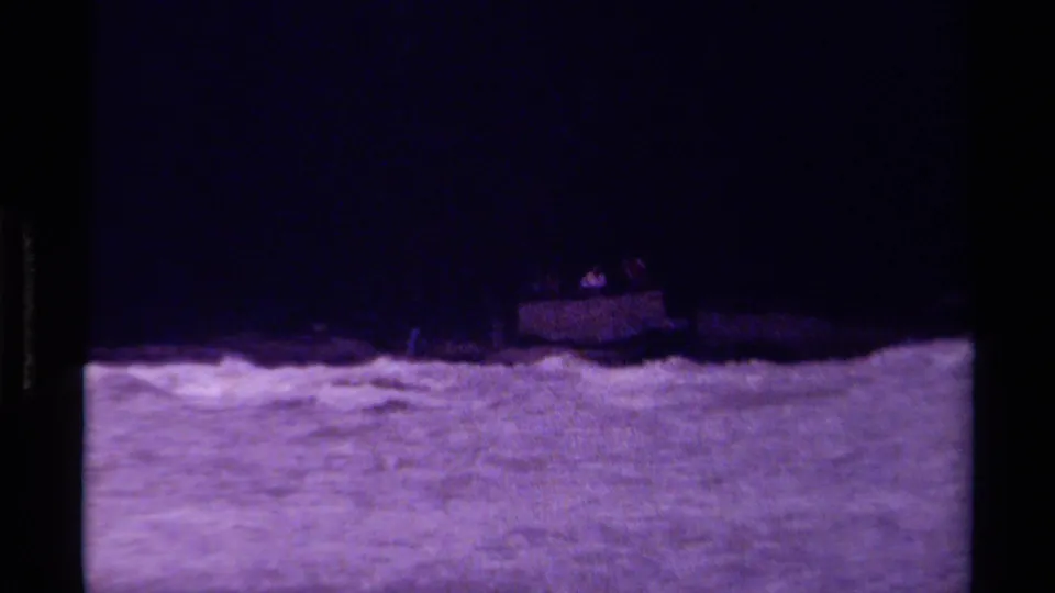 A small distant boat with indistinct figures moves through choppy water near a dark Canadian shoreline.