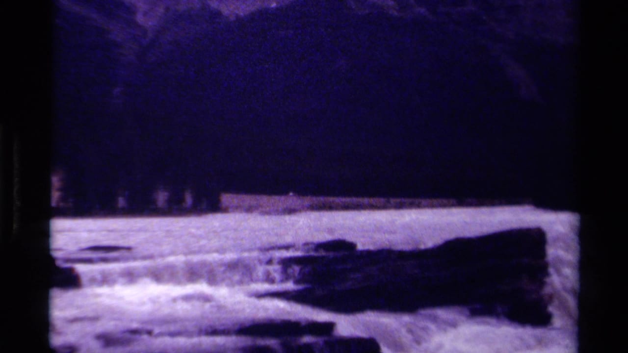 1979 Canada 8mm landscape with forested mountain slopes and whitewater rapids crossing the foreground.