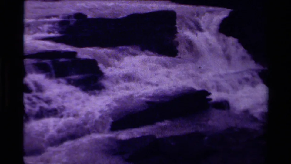 1979 Canada home-movie still showing the waterfall continuing over layered rocks, with soft focus and magenta-purple aging.