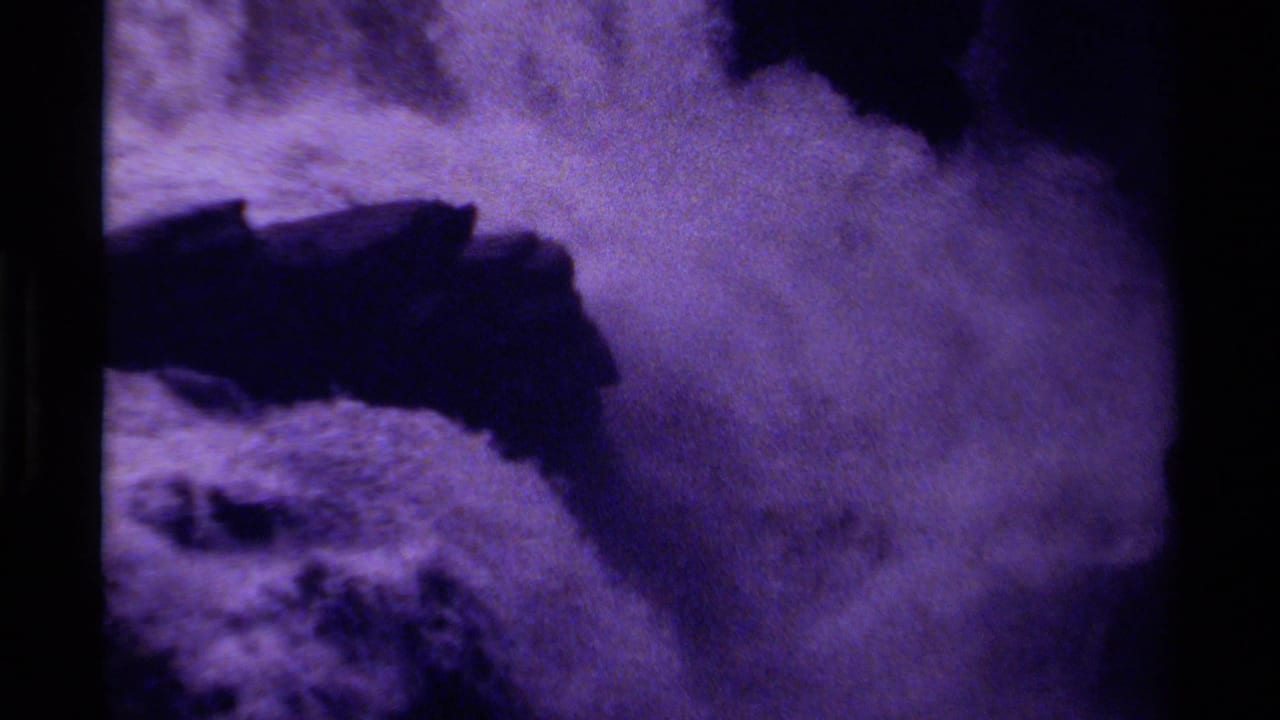 1979 Canadian 8mm frame with rushing waterfall spray, dark rock shapes, and visible grain in a purple-tinted scan.