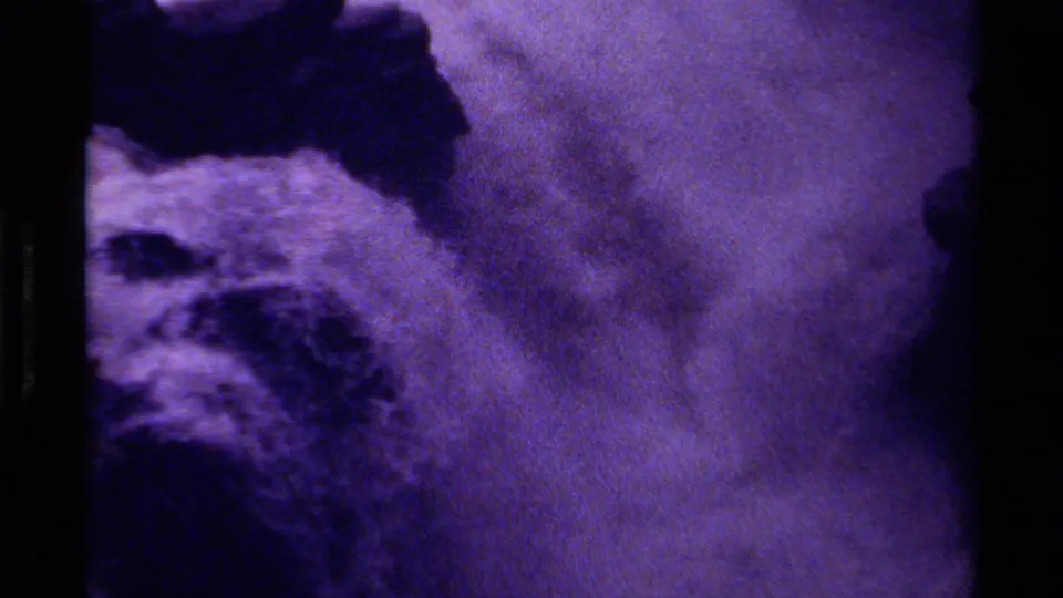 1979 Canadian 8mm frame showing foamy waterfall water beside shadowed rocks, with heavy grain and dark frame edges.