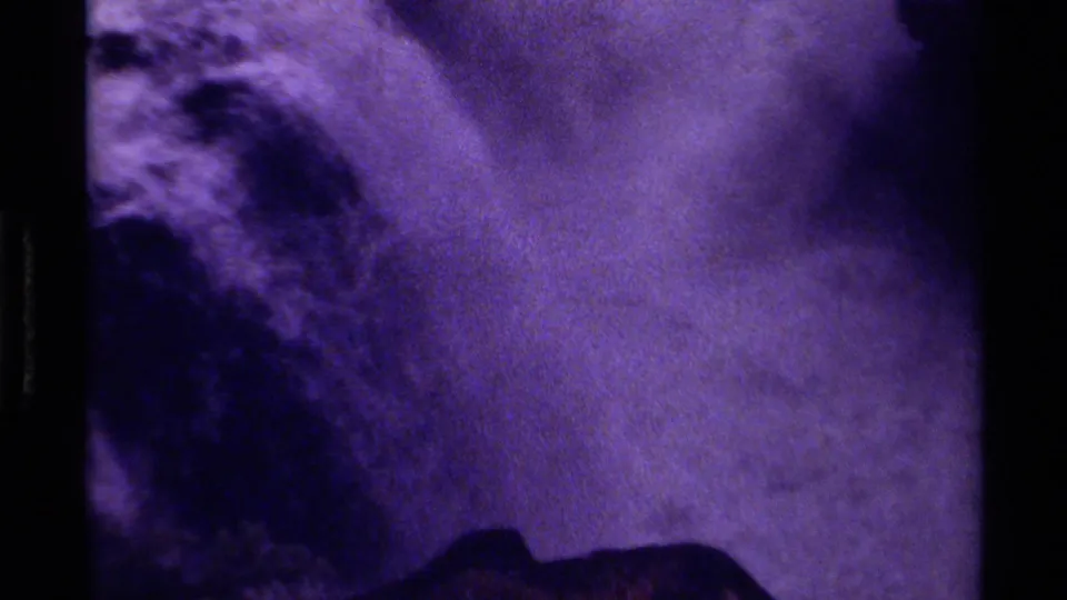 1979 Canadian 8mm frame showing a purple-tinted waterfall or rushing water channel between dark rugged rocks.