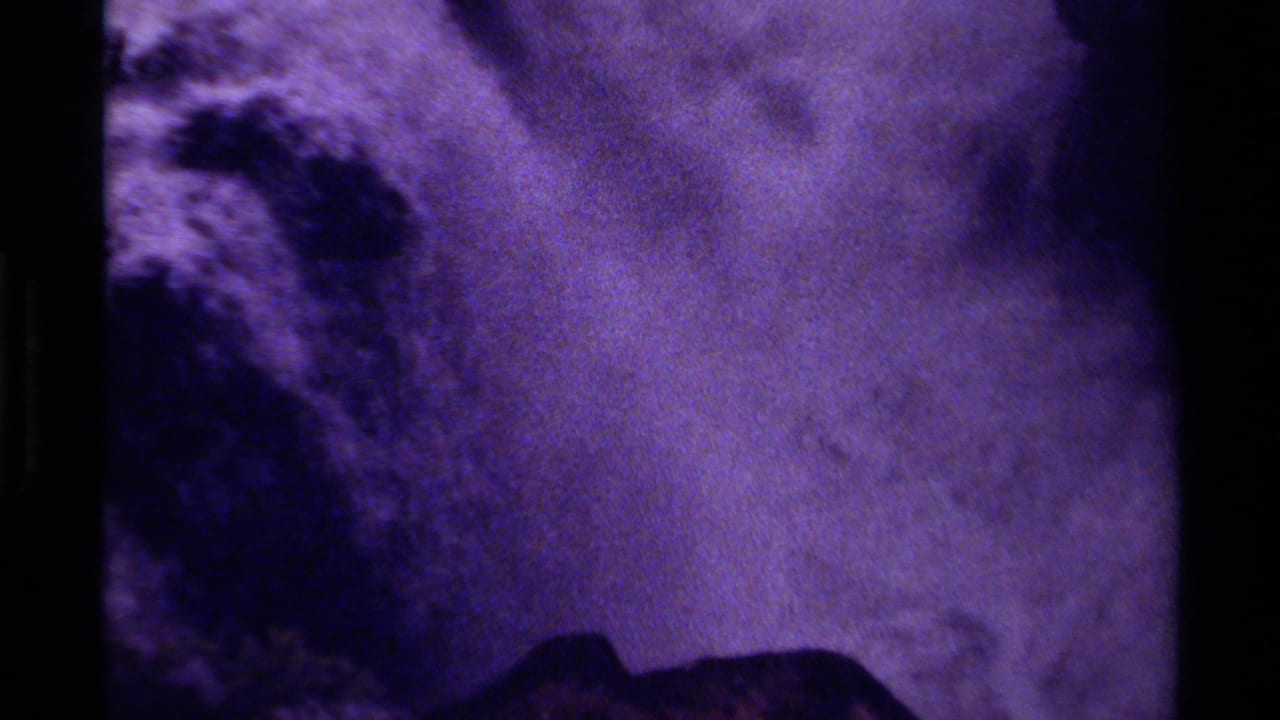 Purple-shifted 8mm frame from Canada showing white water moving through rugged rock formations.