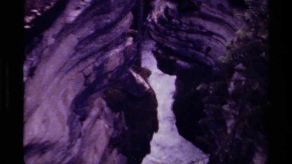 1979 Canada home-movie frame with a closer view of water rushing through purple-tinted layered rock.