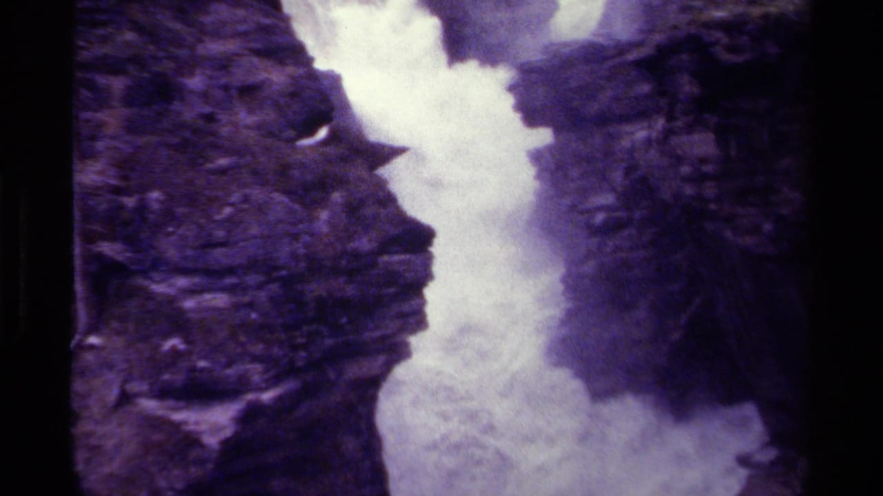 Purple-tinted waterfall rushing between dark rock walls.