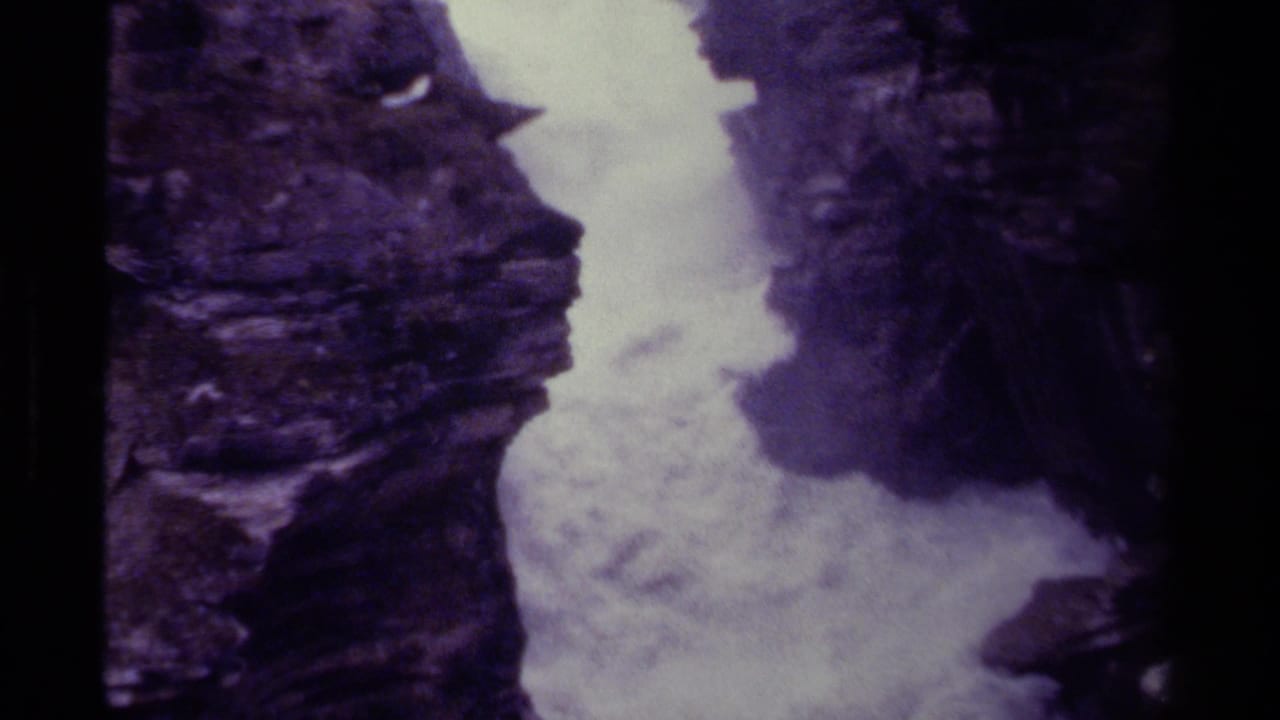 Canadian 8mm home-movie frame of turbulent water filling a narrow gorge, bordered by rugged dark stone.