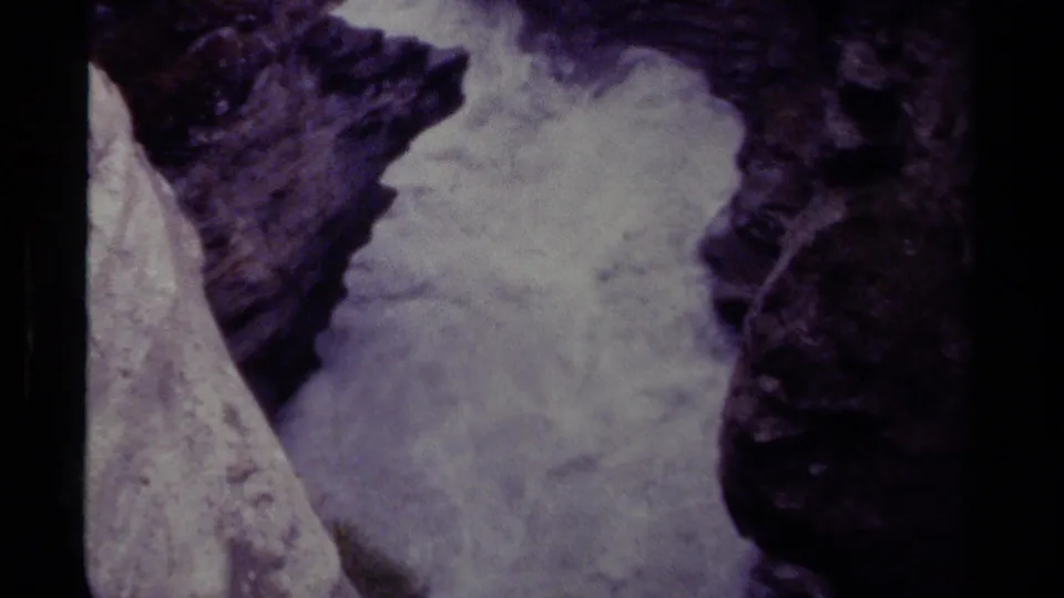 1979 Canadian 8mm frame showing turbulent waterfall flow against steep, shadowed rock surfaces.