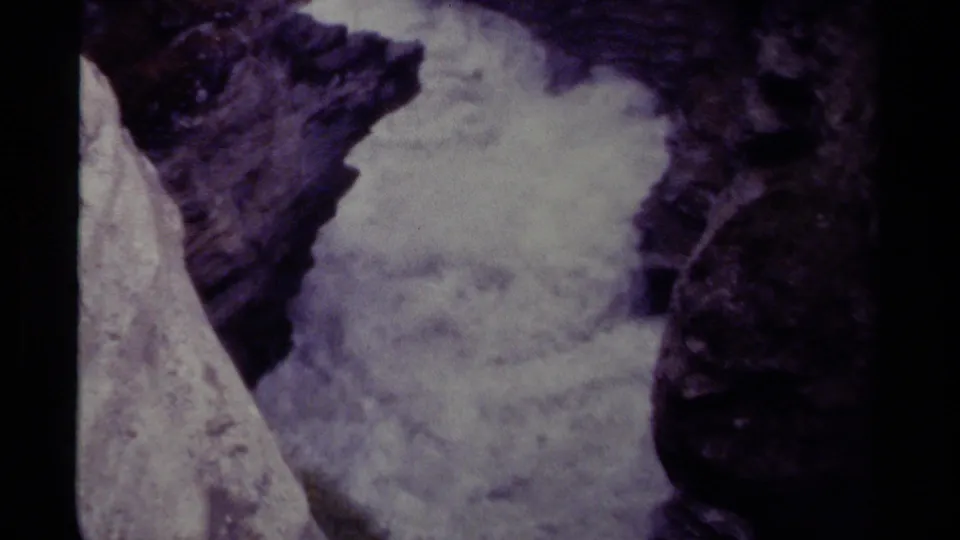1979 Canadian 8mm frame with dense waterfall foam centered between rugged, dark rock walls.