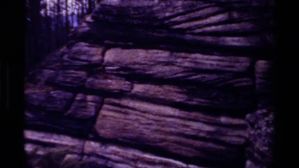 1979 8mm Canada home-movie frame showing layered canyon rock with dark edges and a strong purple color shift.