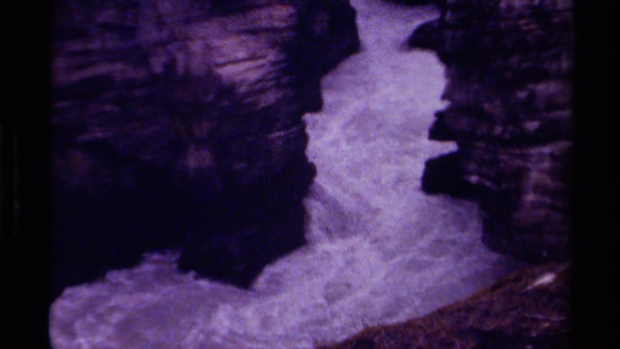 Foaming white water rushes between dark canyon rock walls.