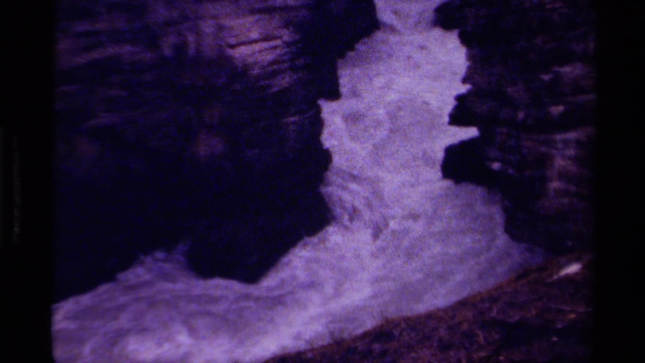 1979 Canada 8mm frame with turbulent white water flowing beside steep dark rock, tinted purple by the film scan.