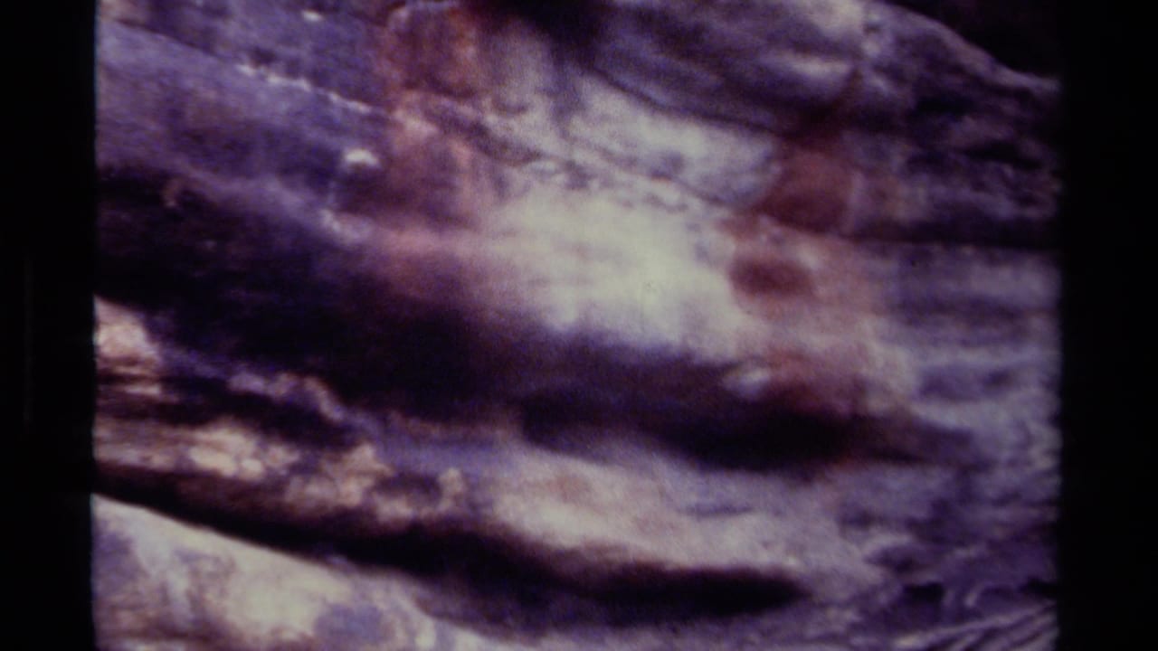 Soft, purple-brown view of rough cave rock with black film borders.