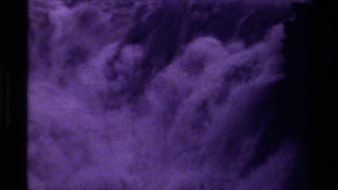 1979 Canadian 8mm frame with purple abstract motion, soft cloudy forms, and dark negative space.