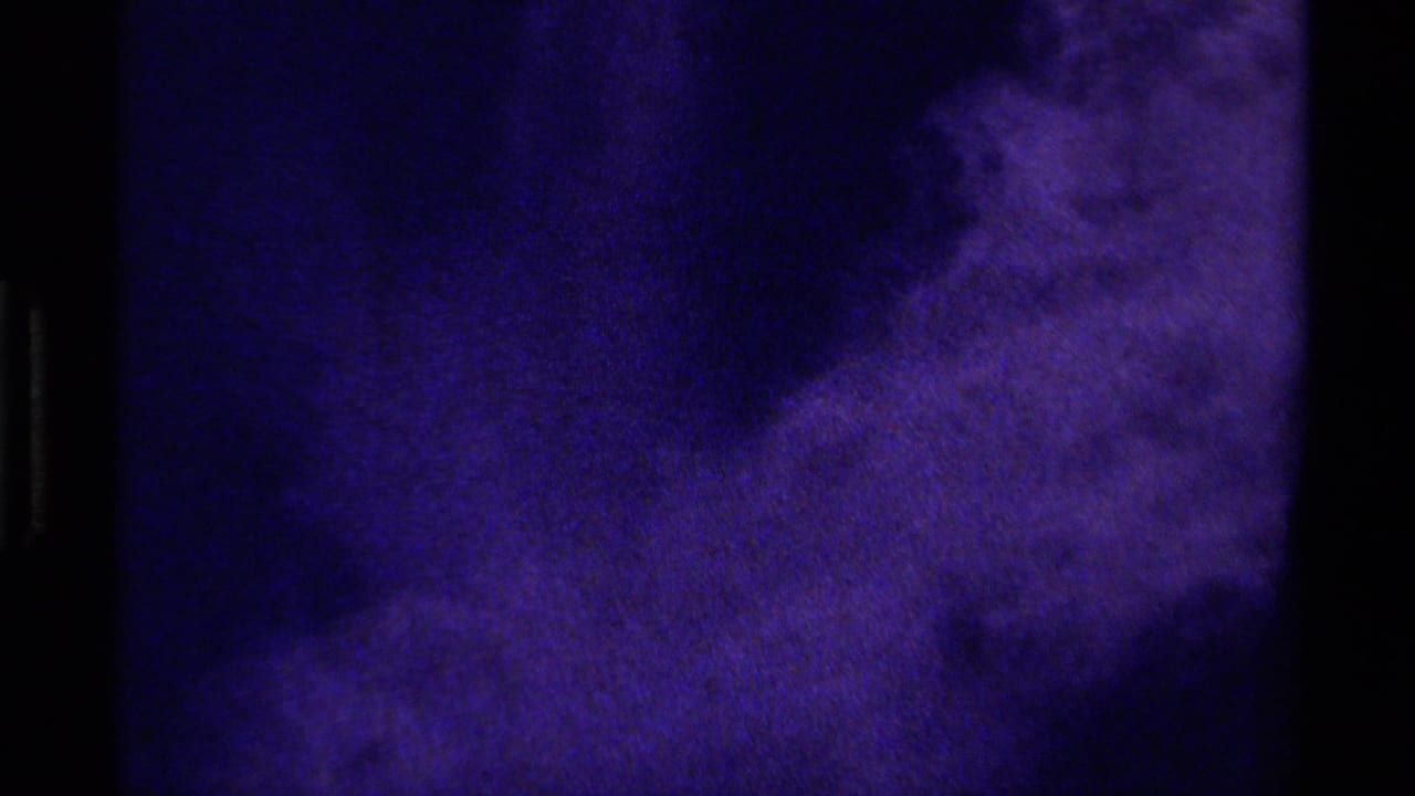 1979 Canada 8mm close-up of a mottled purple-blue glacial surface, with large dark shadow forms and soft grain.