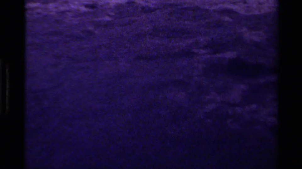 1979 Canadian 8mm frame of rippled water rendered in a deep purple cast, with visible grain and black gate border.