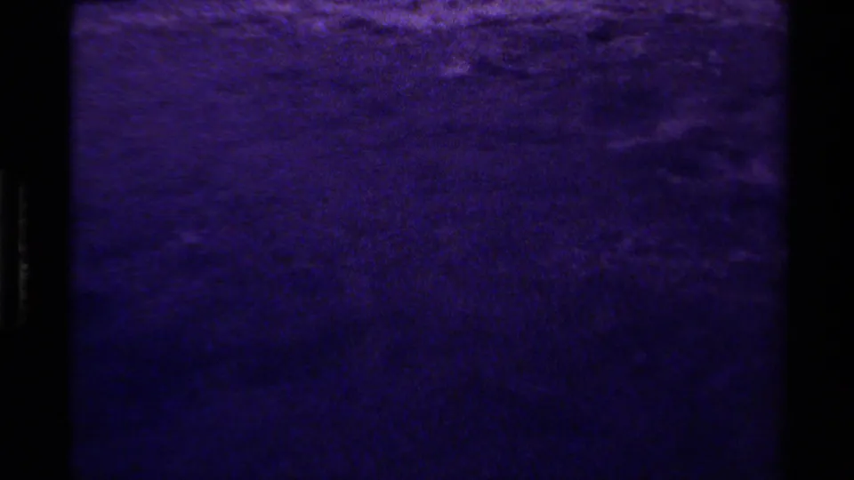 1979 Canadian 8mm frame showing a darker purple water surface with grain, soft ripple detail, and visible gate edges.
