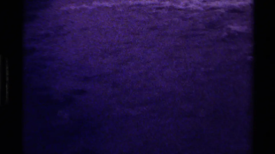1979 Canadian 8mm frame of an abstract purple-blue water surface, softened by grain and bordered by the film gate.