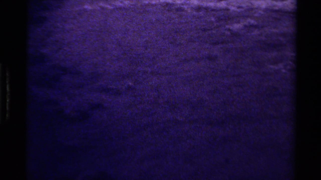 1979 Canada 8mm frame showing dark, softly rippling water with heavy grain and purple-blue aging.