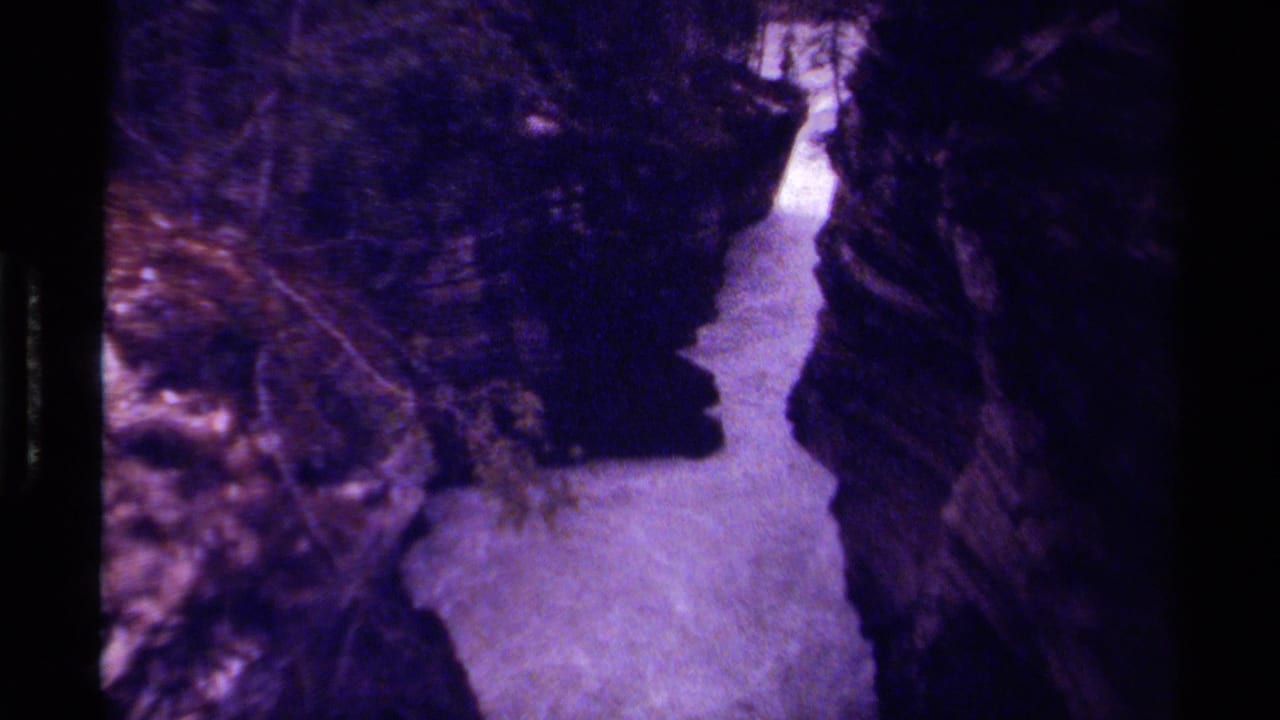 1979 Canadian 8mm frame showing a narrow rocky canyon with water below, dark stone walls, and trees along the top edge.