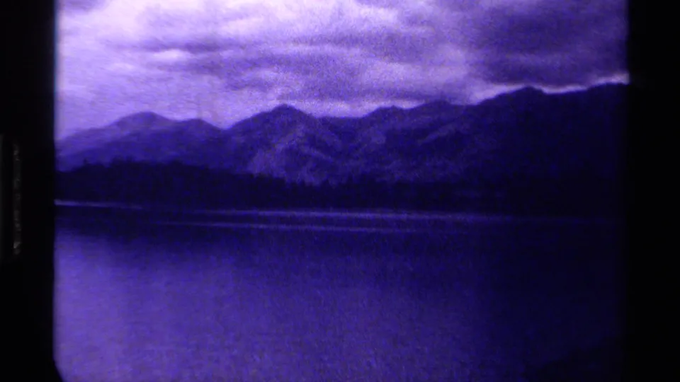 1979 Canadian 8mm landscape showing a lake in the foreground, a dark mountain range, and layered clouds overhead.