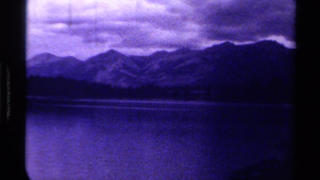 1979 8mm Canada footage appears to show dark mountain ridges beyond a lake, with heavy clouds and a strong purple-blue cast.