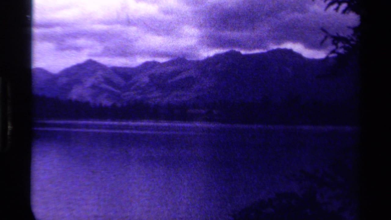 A Canadian mountain landscape from 1979 appears across a lake, with dark ridges, cloudy sky, and visible film-frame borders.