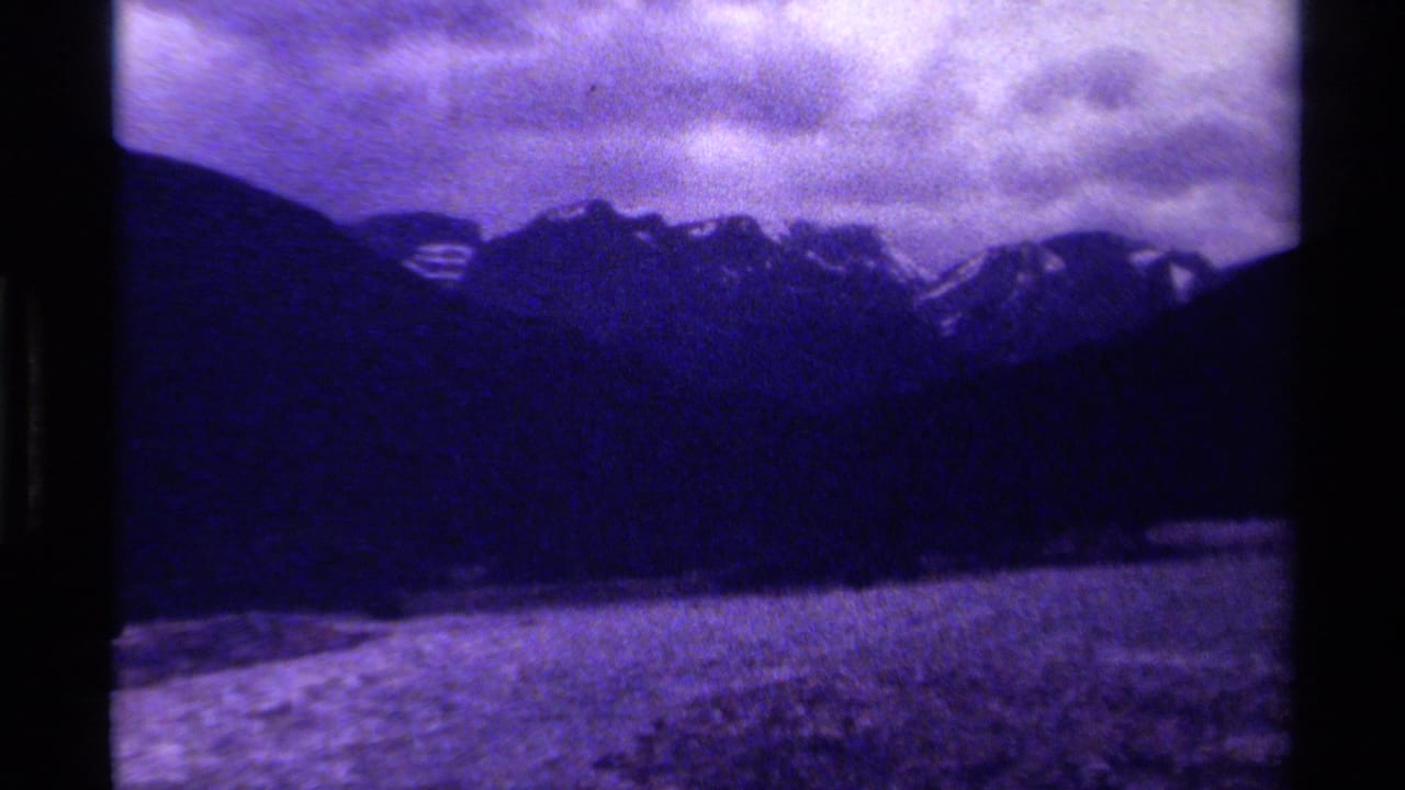 Shadowed mountain range under cloud with a pale foreground strip near the base.