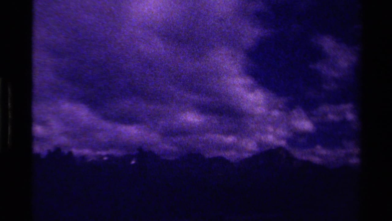 Dark ridgeline under dense storm clouds in a purple-toned frame.