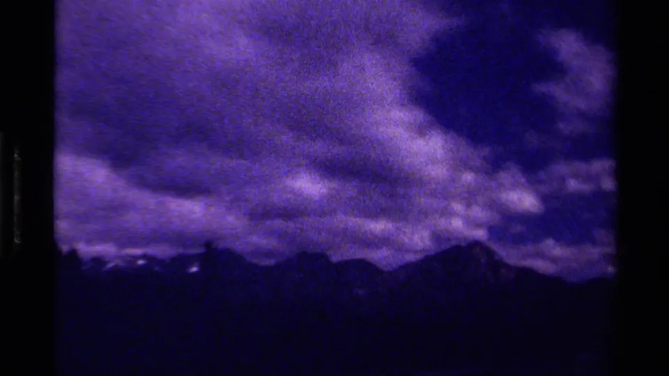 1979 Canadian 8mm frame with broad storm clouds, low mountain silhouettes, and pronounced purple-blue aging.